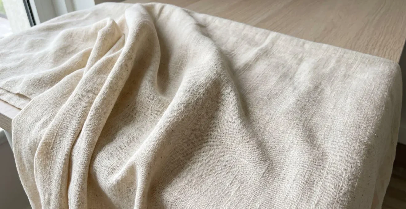 Gros plan macro sur le tissage d'une abaya en lin beige clair révélant la structure aérée de la matière